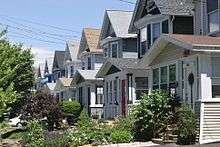 Two-story, single-family homes line a street; the houses are identical in design except for color.