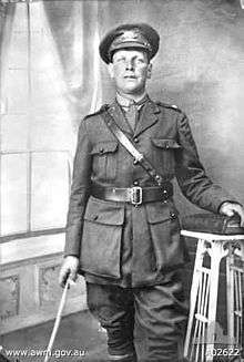 A studio portrait of a military officer in full uniform with cane.