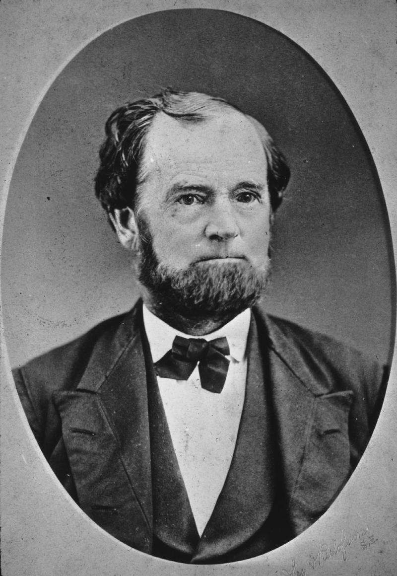 Oval, black and white shoulder-height portrait of a man in his forties or fifties, slightly balding wearing a suit