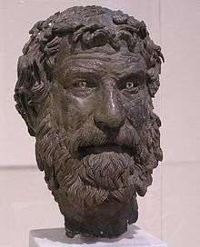 Bronze head of bearded man with furrowed brow and unruly hair