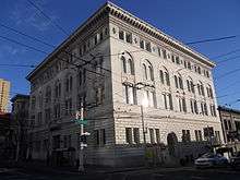 A color photo of a beige four-storied building with arched windows and ornate roof