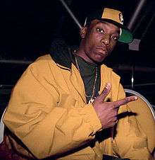 An African-American man, in his early twenties, poses for a camera shot. He is wearing a tan jacket with a tan hat tilted to the side.