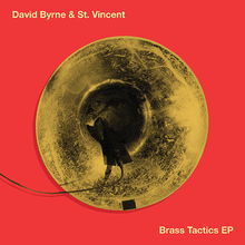 A piece of recording equipment hanging out of a brass horn on an orange background with "David Byrne & St. Vincent" and "Brass Tactics" written in yellow