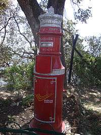 Tall, round red mailbox with decorative crown on top