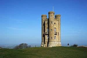 Golden limestone tower with three circular turrets that run the height of the building.