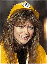 A woman with light brown hair, she wears firefighter hat