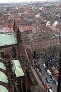 Looking down onto he edge of a cathedral building, with a busy square, in the middle of a city