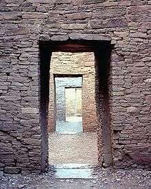 A rectangular entrance through a thick wall dressed with sandstone blocks in the foreground. The entrance reveals a view of another similar wall, itself bearing a doorway showing yet another wall with another door. Four such nested sets of doorways are seen, with a fifth wall visible through the final fourth doorway.