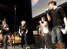 Photograph of a group singing and playing instruments on stage.