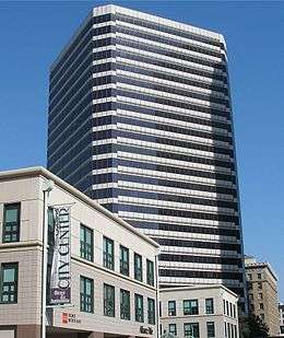 Sideview of a white tall building behind several other short buildings