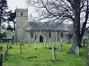 A stone church seen from the south with a battlemented tower on the left