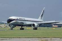 Side view of twin-engine jet touching down on runway, with deployed flaps and thrust reversers.