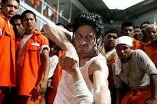 Man in white sleeveless shirt, fighting in a prison