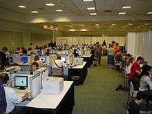 Large room, with reporters at computers in cubicles