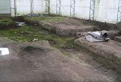 Trenches in bare earth; inside fabric-walled building