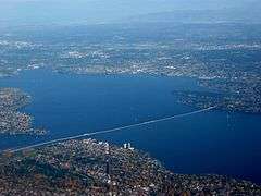 A long floating bridge crossing a lake in a suburban area