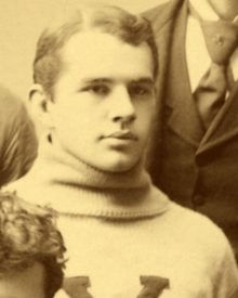 A sepia picture of a young man in a sweater with a "Y"