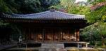 Simple wooden building with slightly raised floor and pyramid shaped roof.