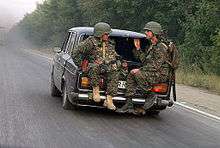 Two soldiers riding in the boot of a car