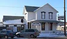 Two-story wooden building with "Glur's Tavern" signs and several modern beer signs