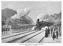 Drawing of steam engine and train approaching station with an honor guard at attention