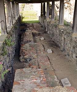 Trench with three grave markers covered by a wooden roof.