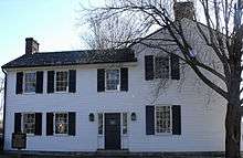 A two-story structure with white siding and windows with black shutters