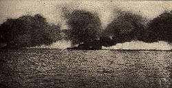 Large ship at sea billowing dark smoke