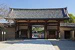 Wooden gate with white walls, red beams and a gabled roof.