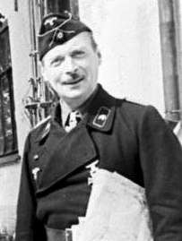 A smiling man in a black uniform holding s sheaf of documents