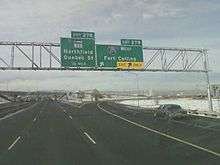 A sign in a snowy area indicating an exit for I-270 to Fort Collins and SH 35 as the next exit