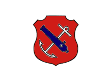 An insignia in the form of a red shield. On the shield are a white anchor crossed by a blue cannon barrel.