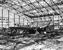 A damaged airplane in a destroyed hangar