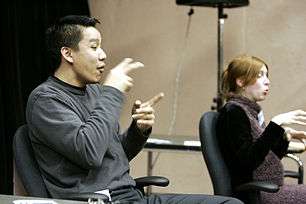 Two seated sign-language interpreters, one male and one female