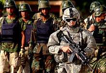 Soldier with machine gun in front of group of uniformed soldiers