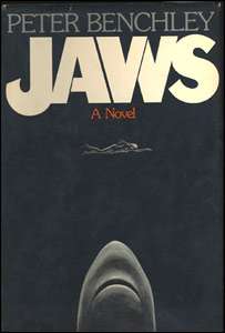 A black cover depicting a woman swimming and a shark coming towards her from below. Atop the cover is written "Peter Benchley", "Jaws" and "A Novel".