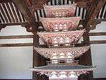 Wooden miniature pagoda with white walls and vermillion red beams.