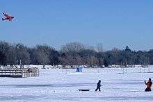 People flying kites on Lake Harriet frozen and covered with snow