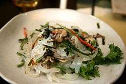 A salad consisting of slices of half transparent jelly-like food and vegetables