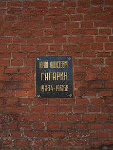 Plaque on a brick wall with inscription: Юрий Алексеевич Гагарин, 1934-03-09–1968-03-27