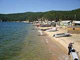 A sandy beach showing cabins and boats drawn up on the shore