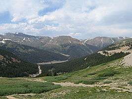 Several mountains with scars from roads visible at the base and up the sides