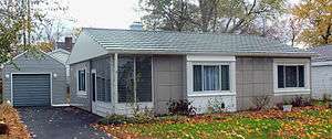 A similar gray house with a driveway on the left leading to a small gray garage