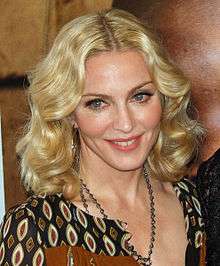 A closeup photo of Madonna with braided hair, heavy makeup and a colorful, low-cut blouse.