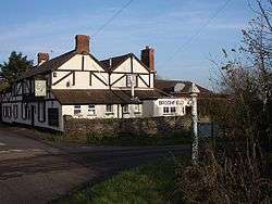 White painted building with black timbers. In the foreground is a road and road sign.