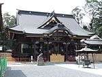 A wooden building with a hip and gable style roof.