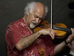 Michael Doucet playing the fiddle at The Dewey Balfa Cajun and Creole Heritage Week at Chicot State Park.  He is wearing a red shirt.