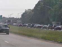 A six-lane freeway with wooded surroundings and a traffic jam