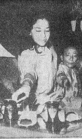 A black and white photograph of a woman shopping for shoes.