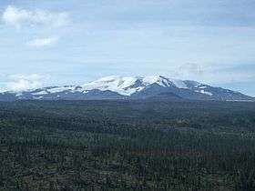 A large open mountain covered with ice and snow rising over the surrounding landscape.